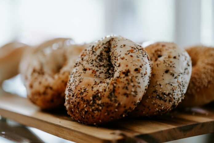Bagels cu semințe de mac și susan, așezați pe o placă de lemn