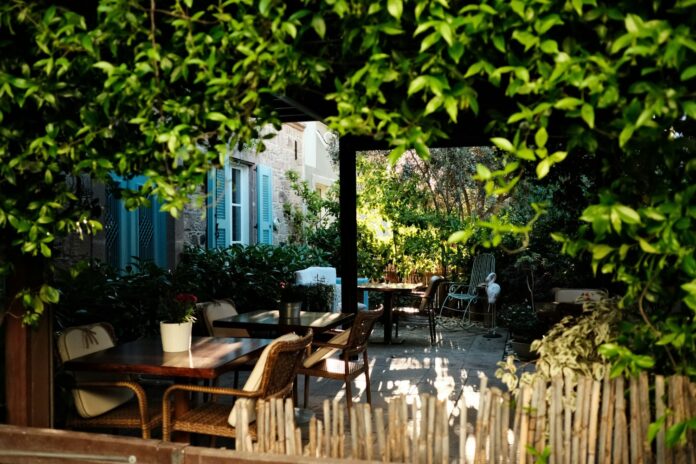 Curte interioară cu mese și scaune între vegetație deasă, într-o grădină de restaurant