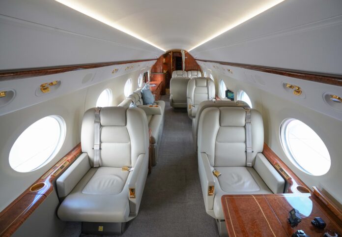 Interiorul unui avion privat Gulfstream G450 NetJets, cu fotolii din piele și finisaje din lemn