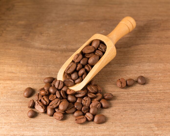 Boabe de cafea prăjită într-o cupă de lemn